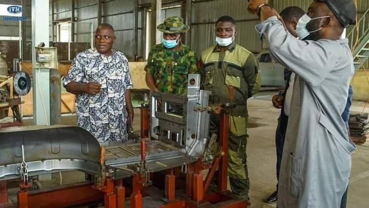 Staff and visitors at a DICON workshop, looking at a vehicle body part on a jig.